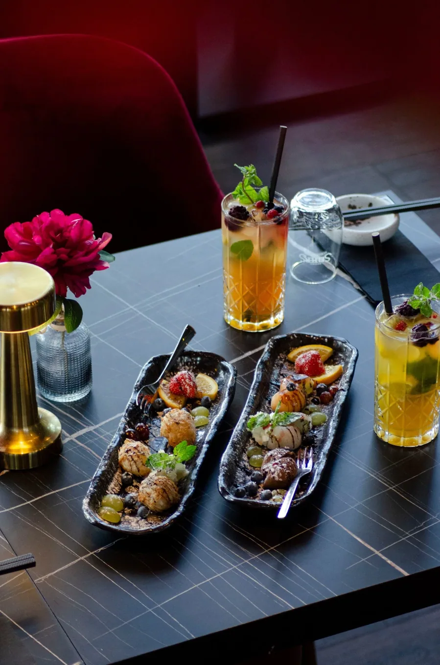 Zwei schwarze Platten mit Karaage, dazu Cocktails und eine Messinglampe