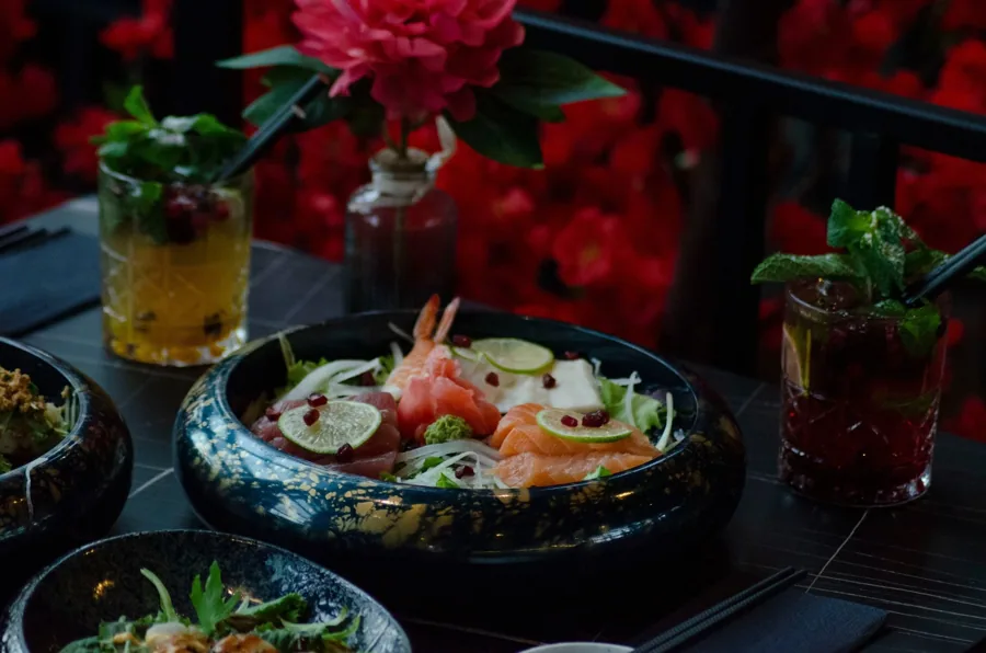 Schale mit Sashimi, daneben Cocktails auf dem Marmortisch