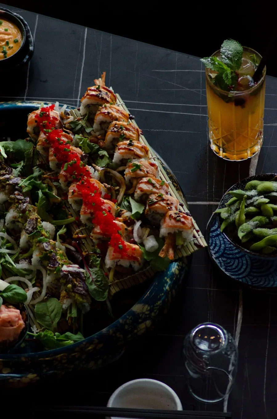 Große Sushi-Platte mit Rollen, Nigiri und Sashimi, daneben Edamame