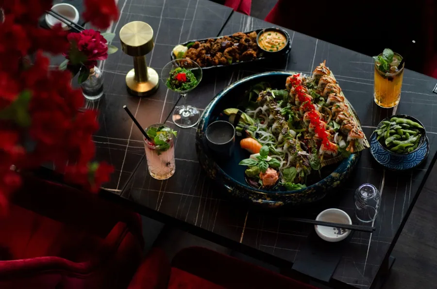 Gedeckter Marmortisch mit Sushi-Platte, Edamame und Cocktails