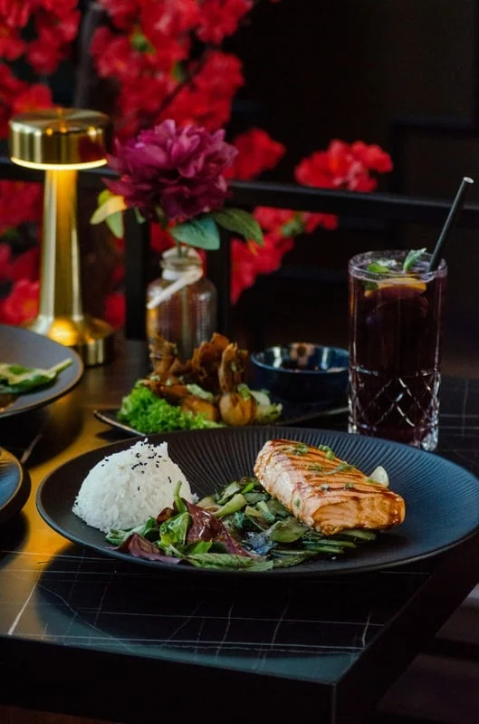 Gegrillter Lachs mit Reis, Gemüse und Salat auf dunklem Teller