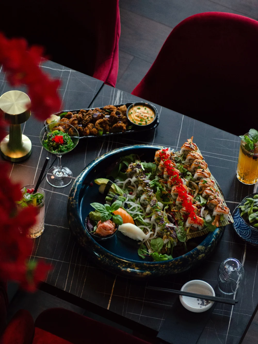 Sushi-Platte, Karaage und Cocktails von oben auf dem schwarzen Marmortisch